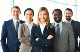 Group of business partners looking at camera with smiles, pretty leader in front